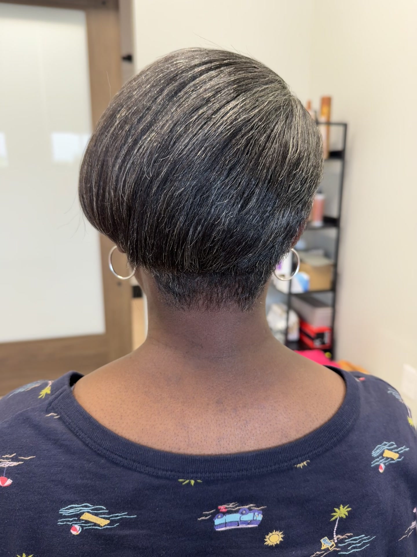 Back view of a short tapered cut with silver and dark strands, close-cropped at the nape.