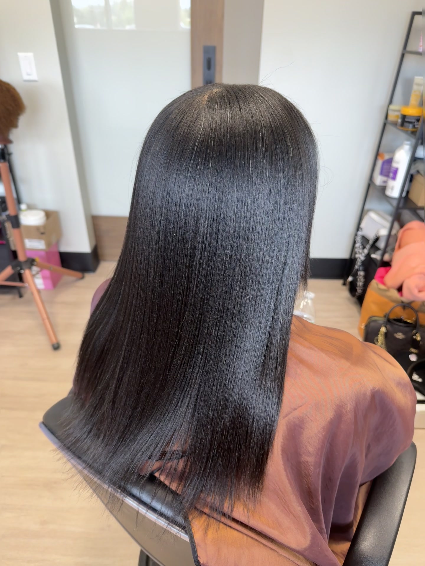Back view of long, smooth dark hair falling past the shoulders with a glossy finish.